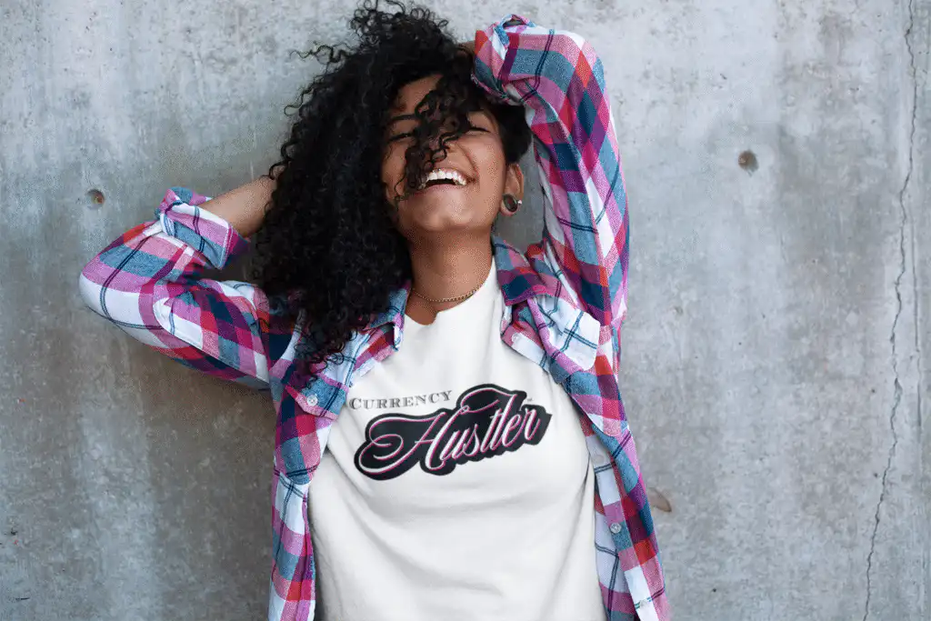 Front view of a happy young woman wearing the Currency Hustler T-shirt by Mastuhree, featuring a bold graphic, premium cotton fabric, and confident streetwear style.