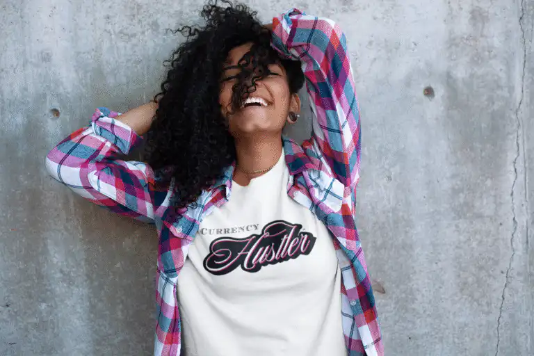 Front view of a happy young woman wearing the Currency Hustler T-shirt by Mastuhree, featuring a bold graphic, premium cotton fabric, and confident streetwear style.