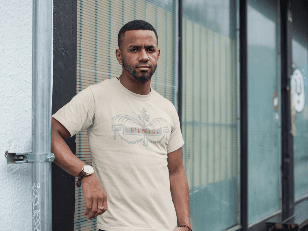 Stylish Black male model wearing oversized luxury streetwear tee by Mastuhree Brand, set against gritty city wall