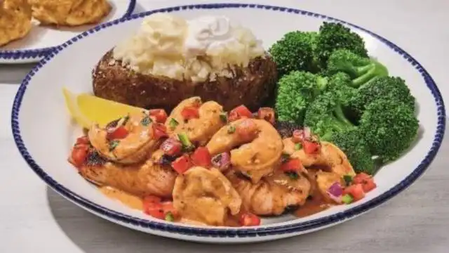 Grilled Salmon New Orleans dish served with shrimp and Cajun butter sauce over seasoned rice.