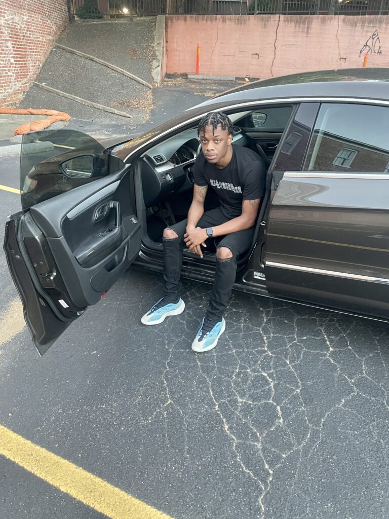 RJay wearing Premium Mastuhree Graphic T-Shirt sitting inside a Volkswagen CC luxury sedan with streetwear-inspired fashion style