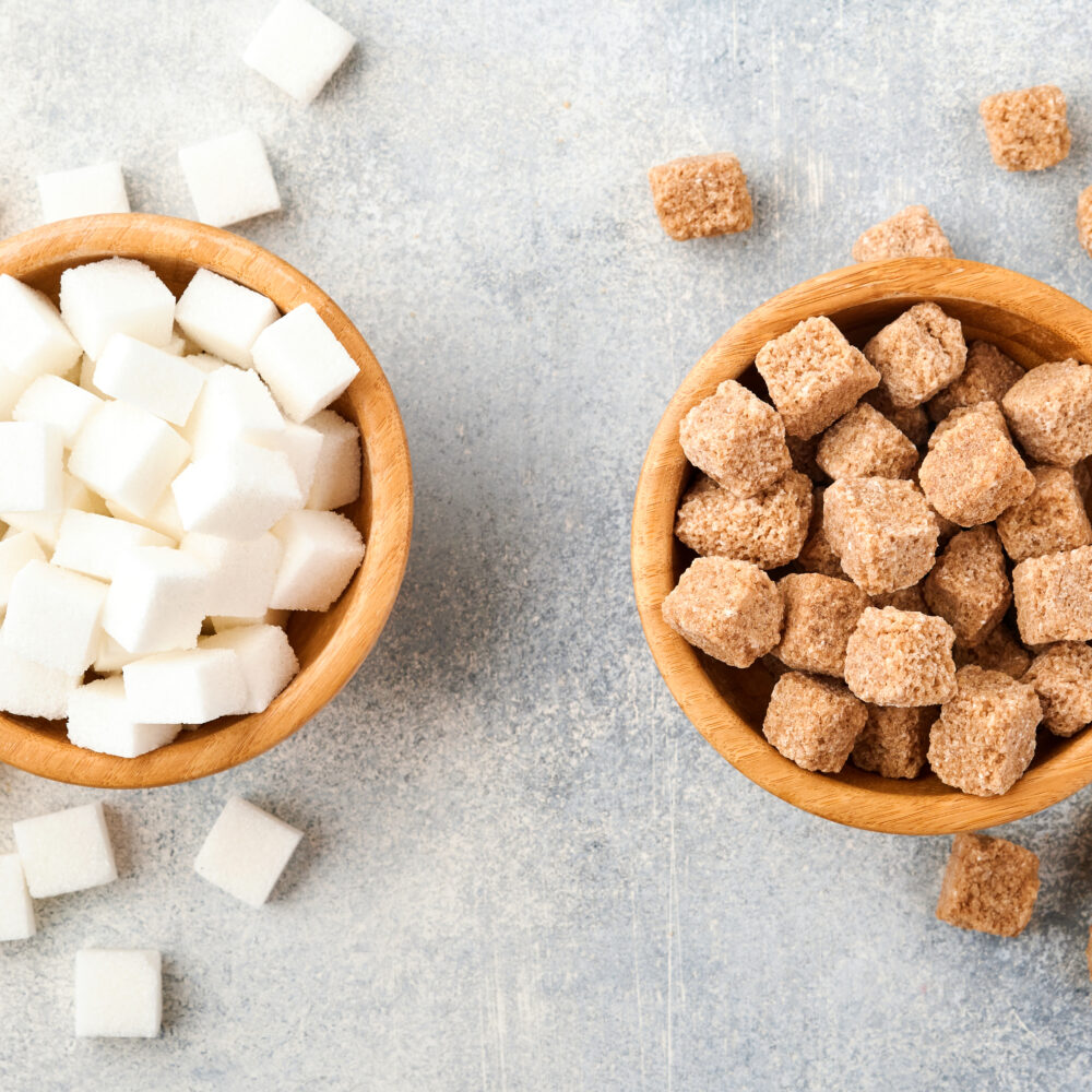 Coffee cup with artificial sweetener packets next to raw sugar, representing the comparison between sucralose, aspartame, and natural sugar