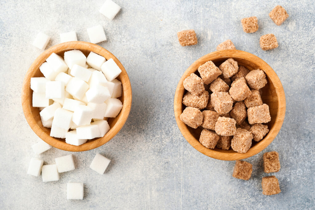 Coffee cup with artificial sweetener packets next to raw sugar, representing the comparison between sucralose, aspartame, and natural sugar