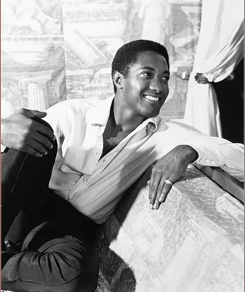 Sam Cooke relaxing on a couch smiling