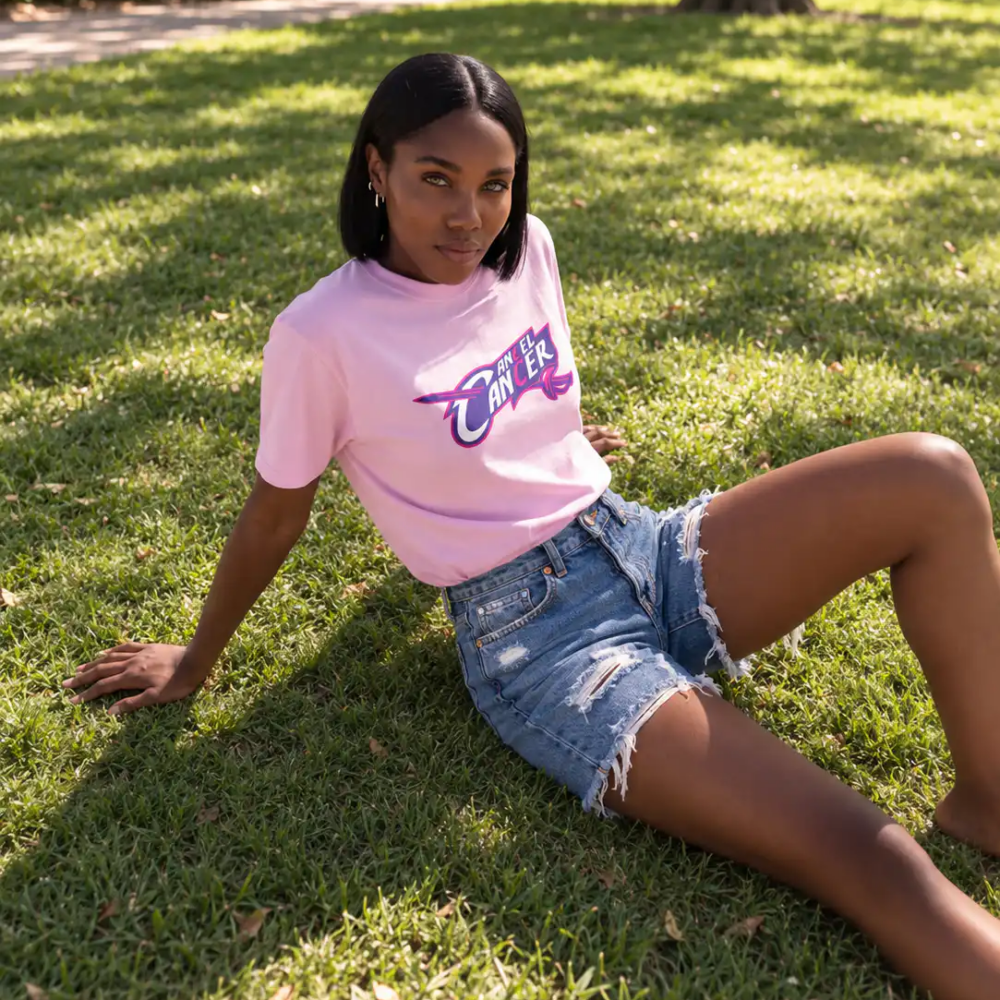 Woman wearing a pink Mastuhree Cancel Cancer graphic T-shirt outdoors, representing continued breast cancer support beyond October.