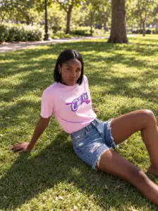 Woman wearing a pink Mastuhree Cancel Cancer graphic T-shirt outdoors, representing continued breast cancer support beyond October.