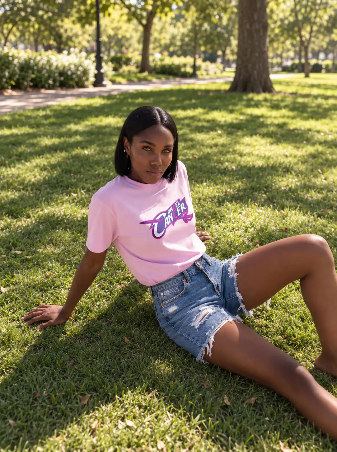 Woman wearing a pink Mastuhree Cancel Cancer graphic T-shirt outdoors, representing continued breast cancer support beyond October.